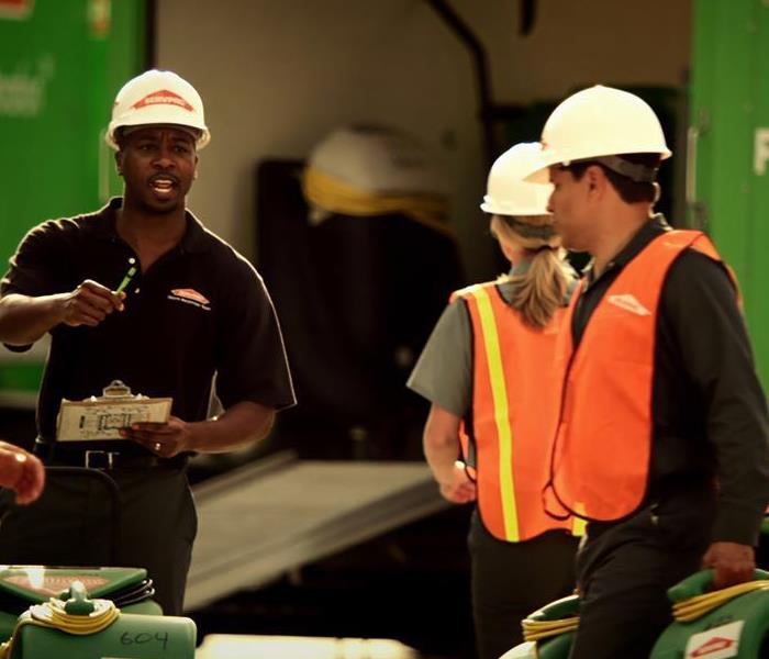 Man holding a clipboard and directing other employees holding work fans