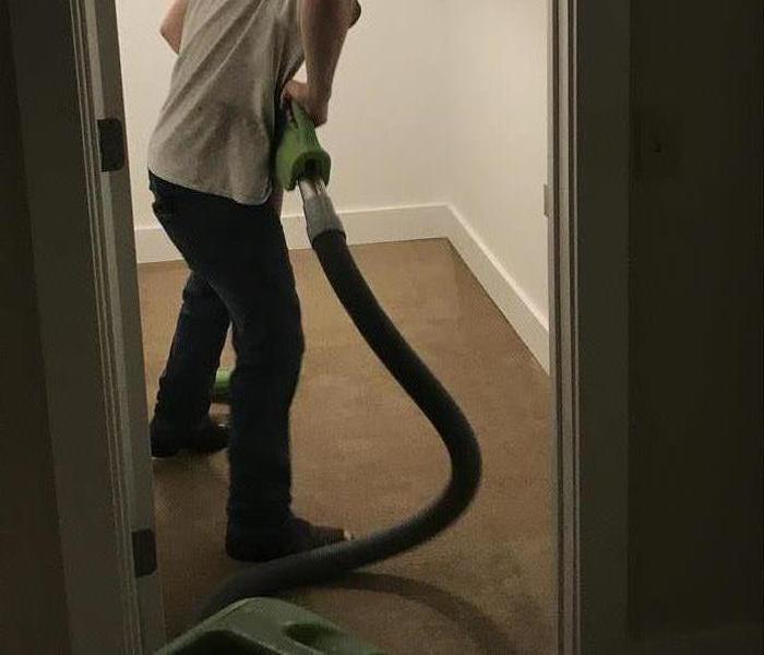 Guy removing water from carpet with a extraction wand