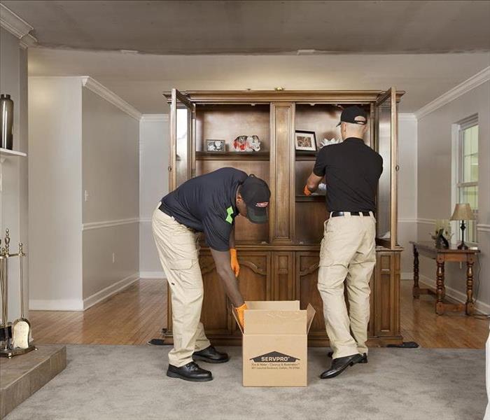 Two workers  placing items from a cabinet into a SERVPRO  box 